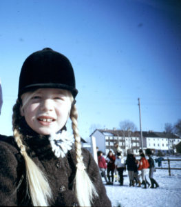 Kiki ist als Kind zu sehen mit Reitkappe und Zöpfen